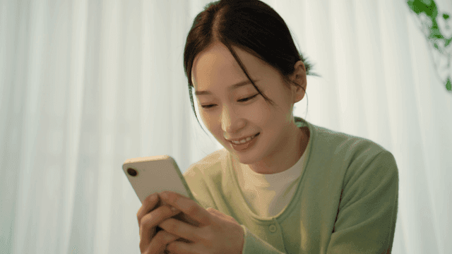 Woman smiling while looking at her smartphone