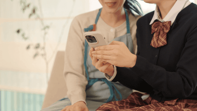 Daughter teaching her mother how to use cell phone.