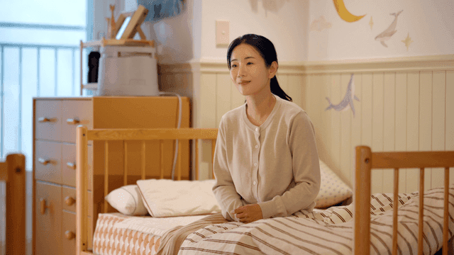 Woman sitting on her bed in her child's room reminiscing