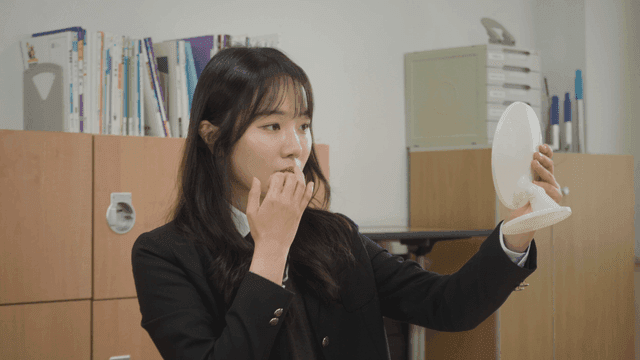 거울을 보며 외모를 확인하는 학생