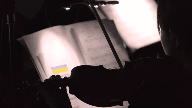 Playing violin on dark stage