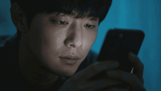 어두운 방 스마트폰 화면에 집중하는 피곤한 남자