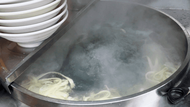 Noodles boiling in a pot with steam
