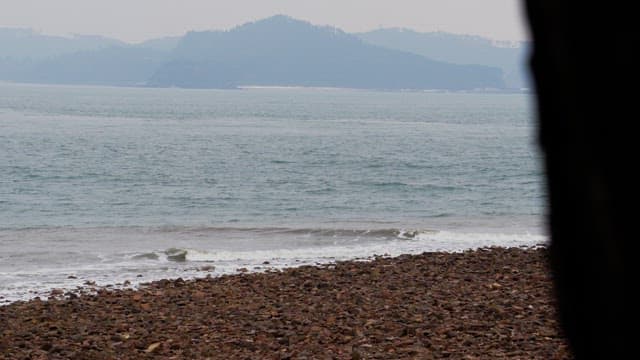 Calm beach facing a serene ocean under a cloudy sky