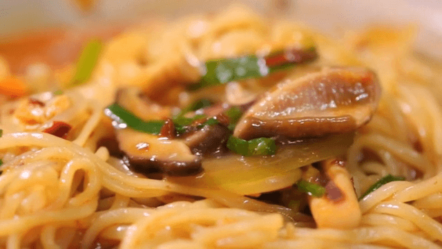 Spicy seafood noodle soup being lifted with chopsticks