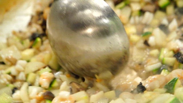 뜨거운 팬에서 볶아지는 우렁이와 다진 채소들