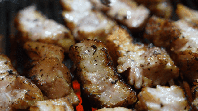 Grilled pork belly sizzling on a grill