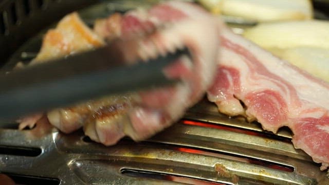 Grilling pork belly on a metal grill