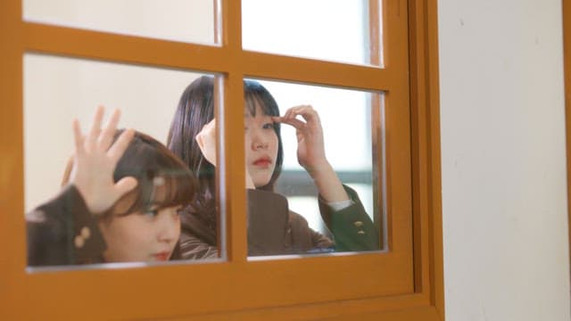 복도에서 교실 창문을 통해 안을 보는 학생들