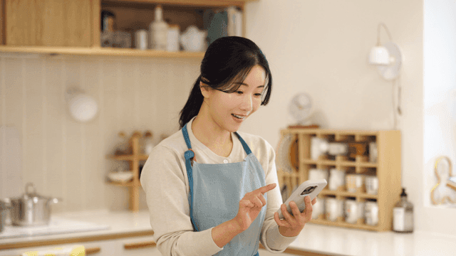 Woman in kitchen using smartphone