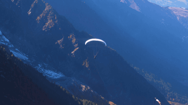 Paraglider soaring over mountain landscape