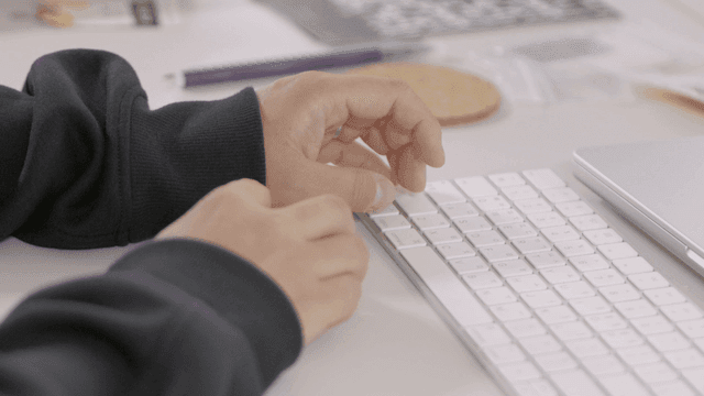 Hands typing on a white keyboard