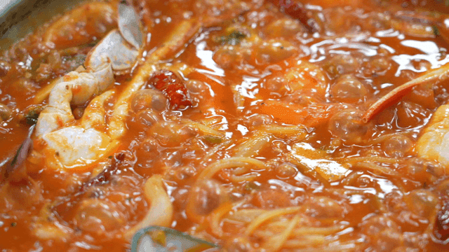 Seafood tomato pasta boiling in pot