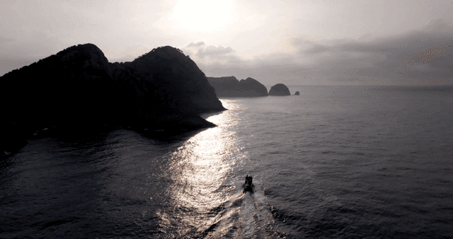 바위 섬 근처를 항해하는 보트