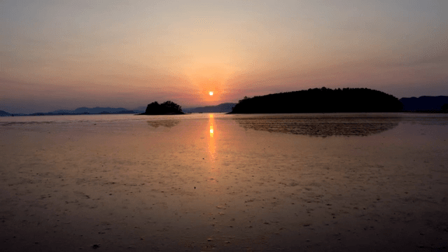 Sunset over a calm sea with distant islands