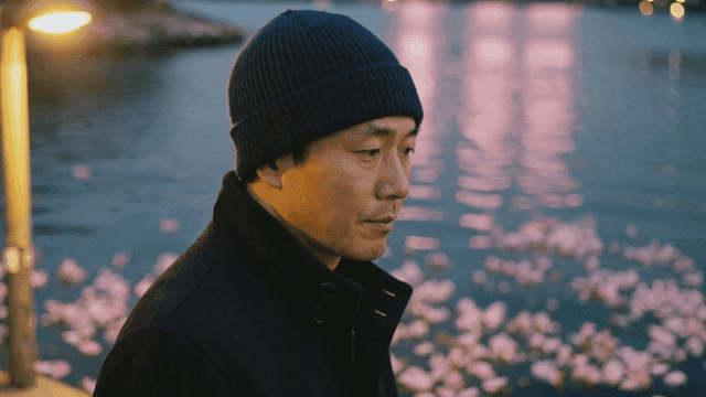 Man standing by lake and fallen cherry blossom petals