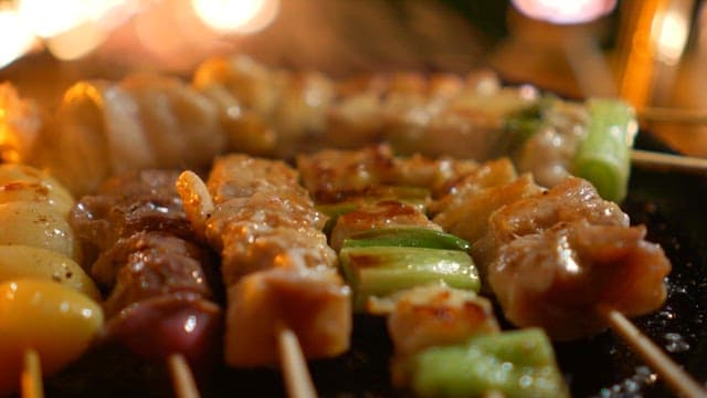 뜨거운 팬 위에서 조리되는 꼬치 위에 후추를 뿌리는 모습