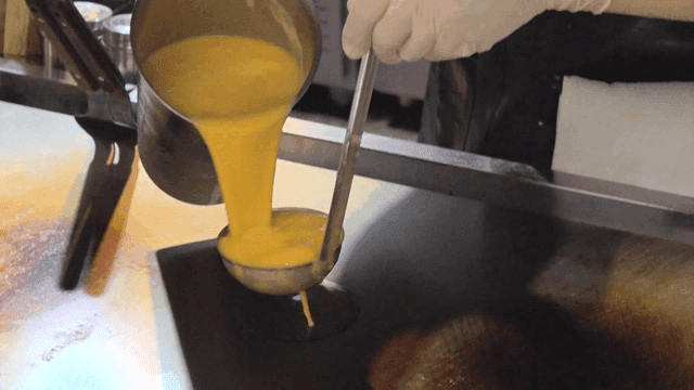 주방에서 철판에 계란물을 붓는 요리사