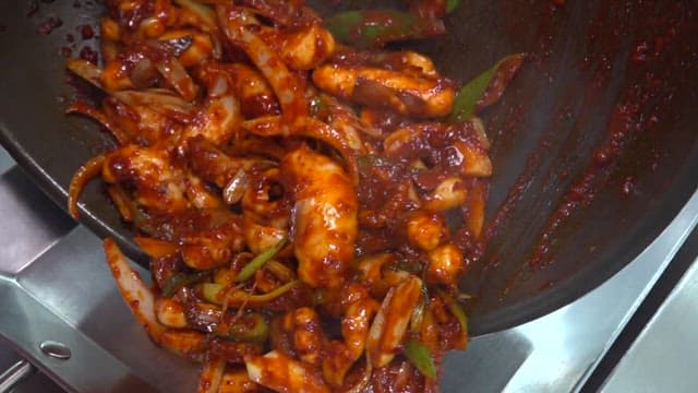 Stir-fried octopus with spicy sauce prepared in a restaurant kitchen