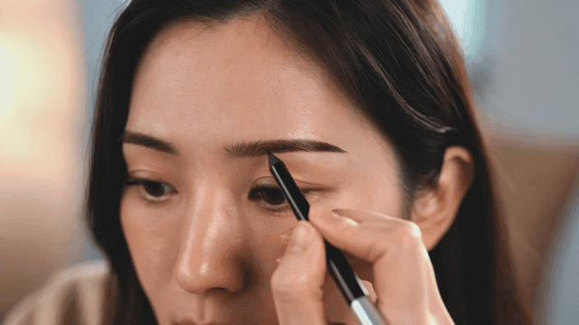 Woman using eyebrow pencil for makeup