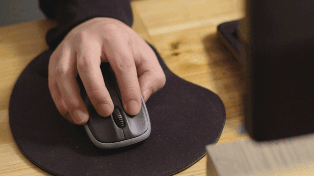 책상 위에서 컴퓨터 마우스를 사용하는 손