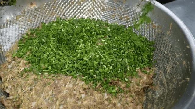 Adding chives to dumpling filling