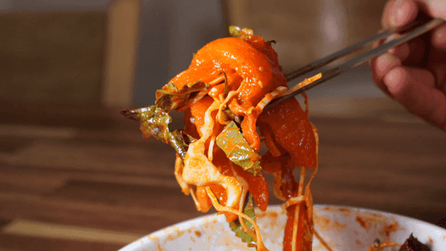 Chopsticks lifting spicy trout sashimi with vegetables
