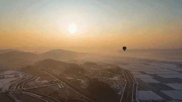 Hot air balloons above serene landscape at sunset