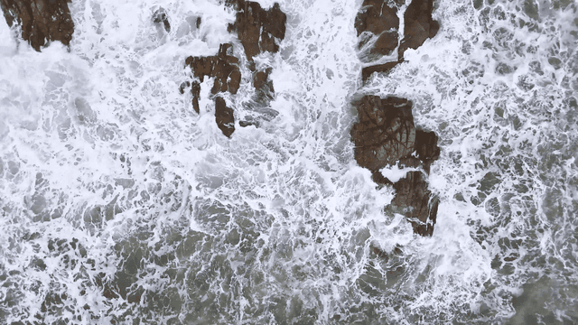 험한 바위 틈을 때리는 하얀 거친 파도