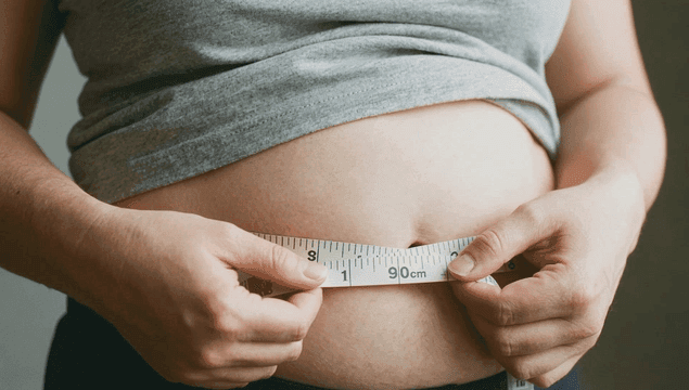 Person measuring waist with tape measure