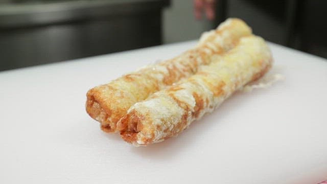 Cutting fried spring rolls made with chives on a cutting board