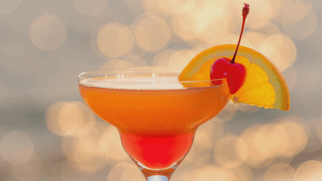 Fancy cocktail with cherry and orange garnish