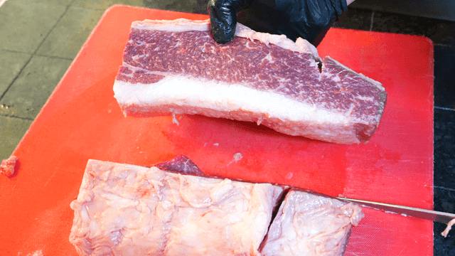 Whole beef brisket cut on red cutting board