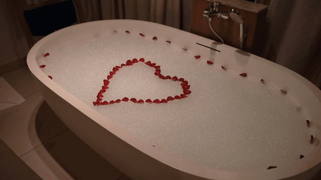 Bathtub with rose petals in heart shape