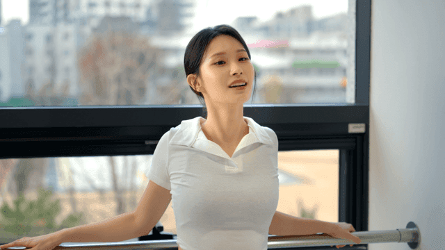 창가에 서서 스트레칭하고 미소짓는 젊은 여성