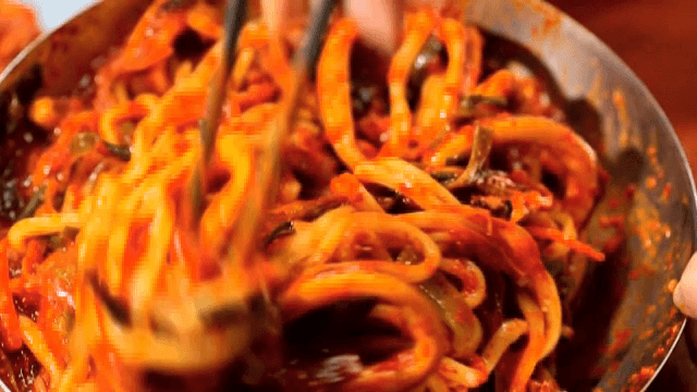 Mixing the spicy stir-fried squid and noodles with chopsticks