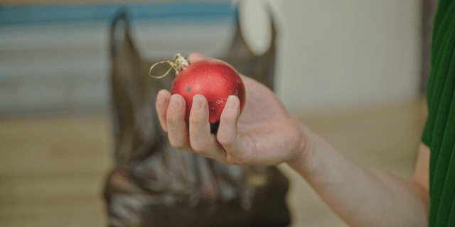 A person holding a red Christmas ornament