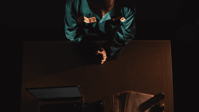Prisoner sitting at desk being interrogated