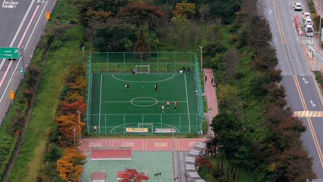 야외 풋살장에서 공을 차는 사람들