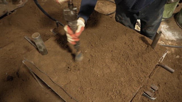 Worker compacting soil in a mold