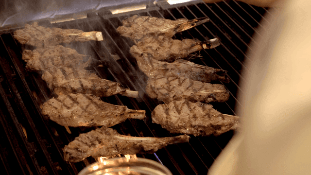 Chef salting lamb ribs on grill