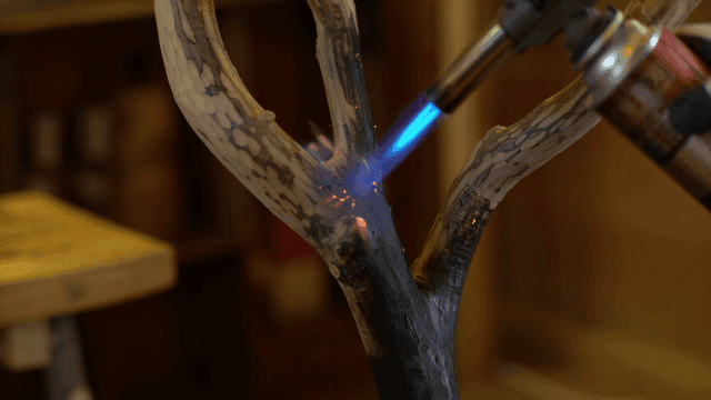 나무에 토치로 불을 붙이는 장면