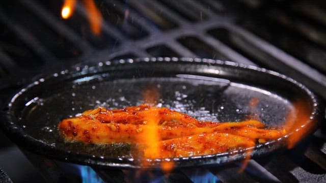 뜨거운 철판에서 요리되는 매콤한 양념 더덕구이