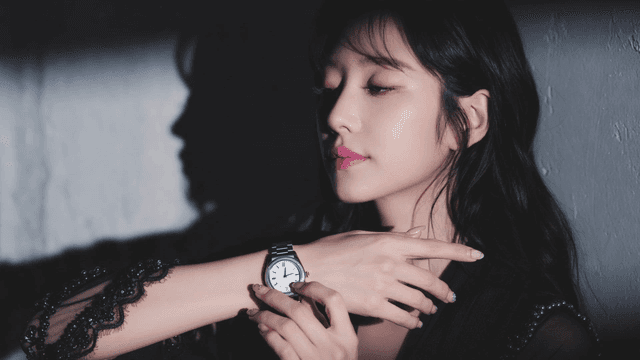 어두운 곳에서 손목시계를 만지는 젊은 여성