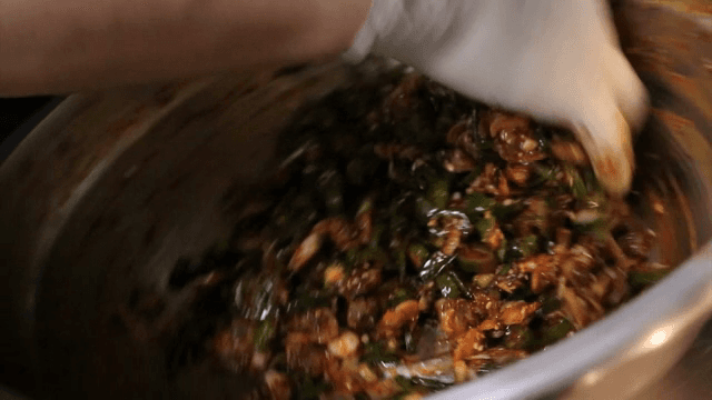 대야에서 양념과 꼬막을 무치는 모습