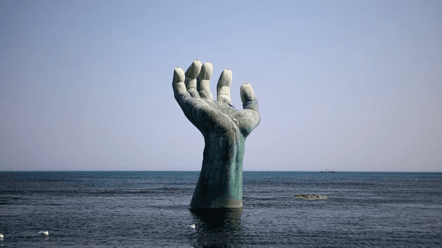 갈매기와 함께 바다에 있는 큰 손 조각상