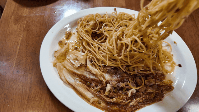Fork picking up plate of pasta with vegetables