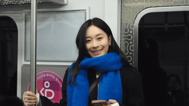 Woman smiling while looking straight ahead on the subway