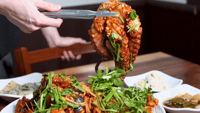 Spicy seafood stew octopus lifted with tongs