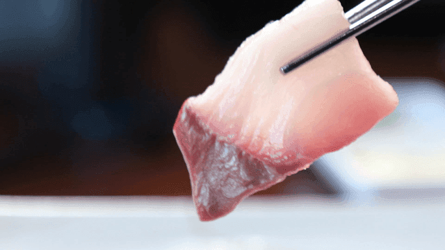 Fresh raw yellowtail picked up with chopsticks